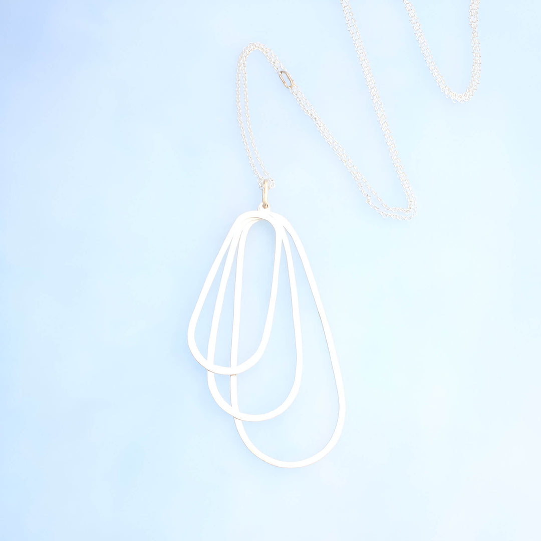 Silver pendant of three layered ovals and a silver rolo chian with 14k gold accents