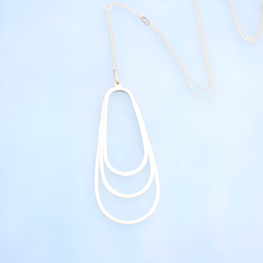 3 inch silver pendant with three layered ovals  on a silver rolo chain with 14k gold oval as the chain closure and pendant attachment