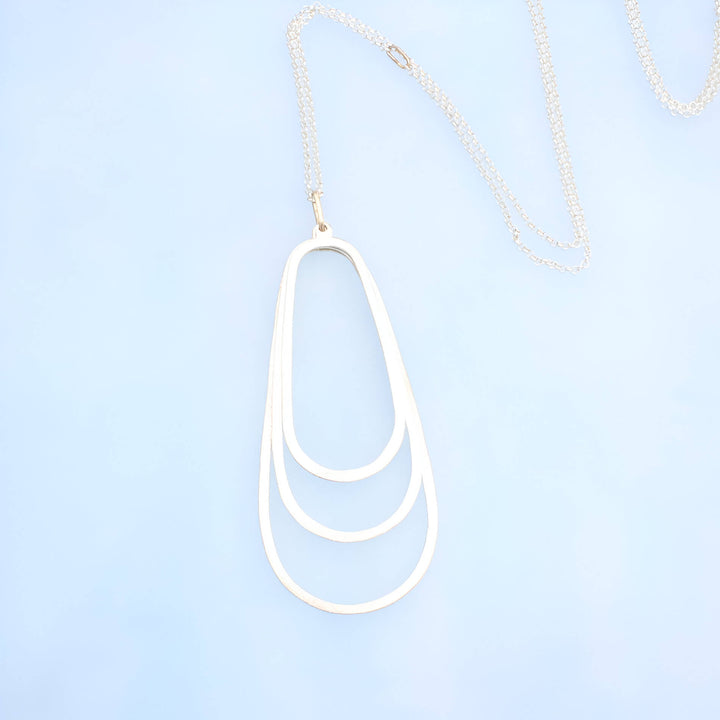 3 inch silver pendant with three layered ovals  on a silver rolo chain with 14k gold oval as the chain closure and pendant attachment