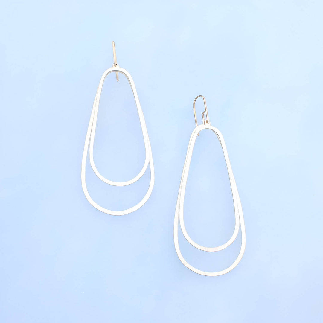 Solid gold ear wires with two recycled silver ovals one larger with a smaller overlapping oval on top.