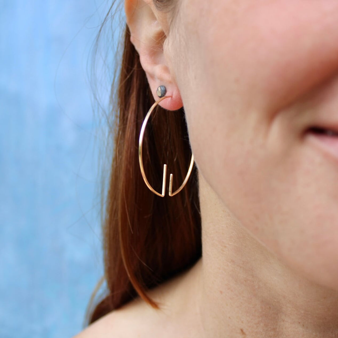 Model wearing 14k gold version of Inverse deco hoops. 1.75 inch open hoop, art deco inspired, minimal earrings