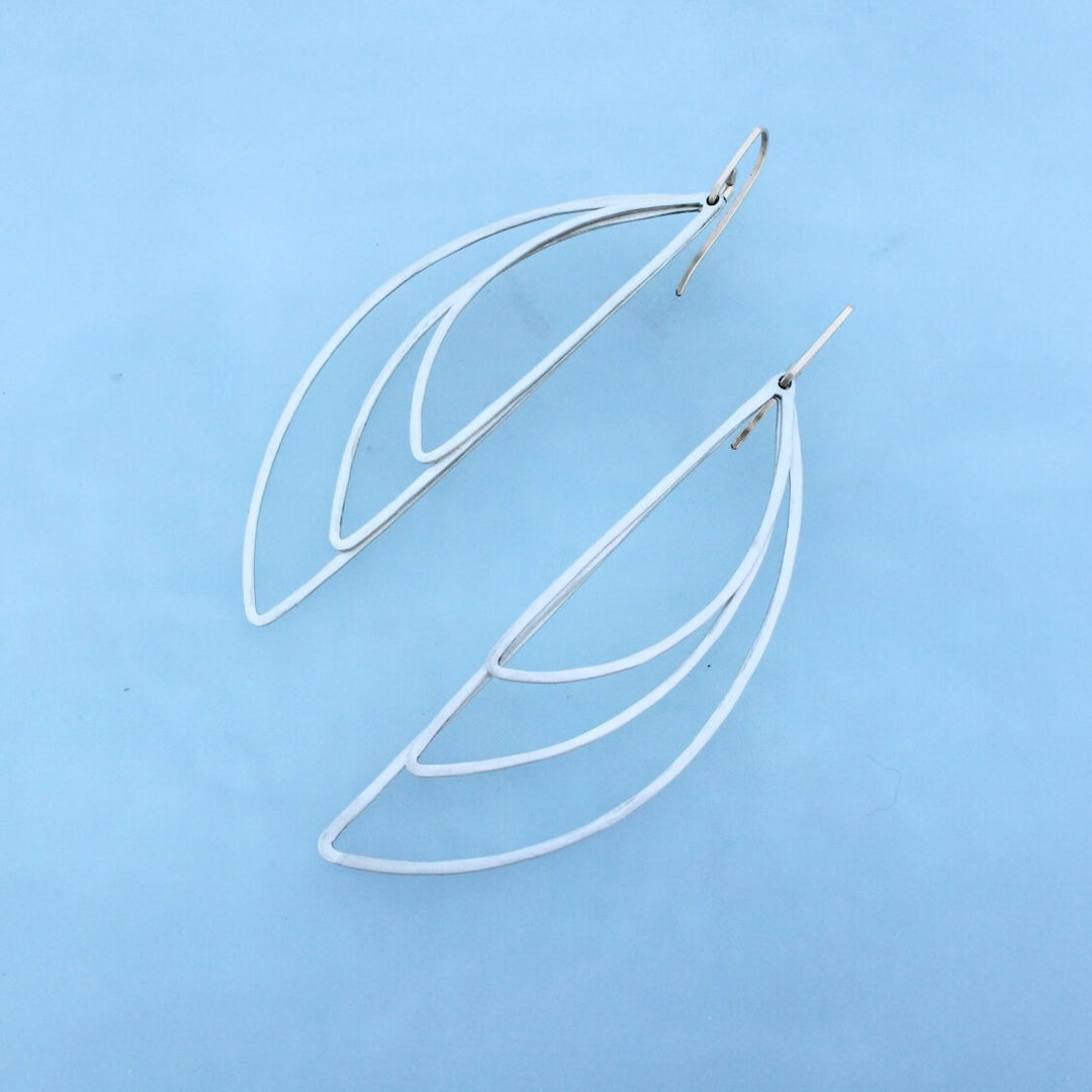 Gold ear wires and silver semicircles. three wire forms layered on top of eachother