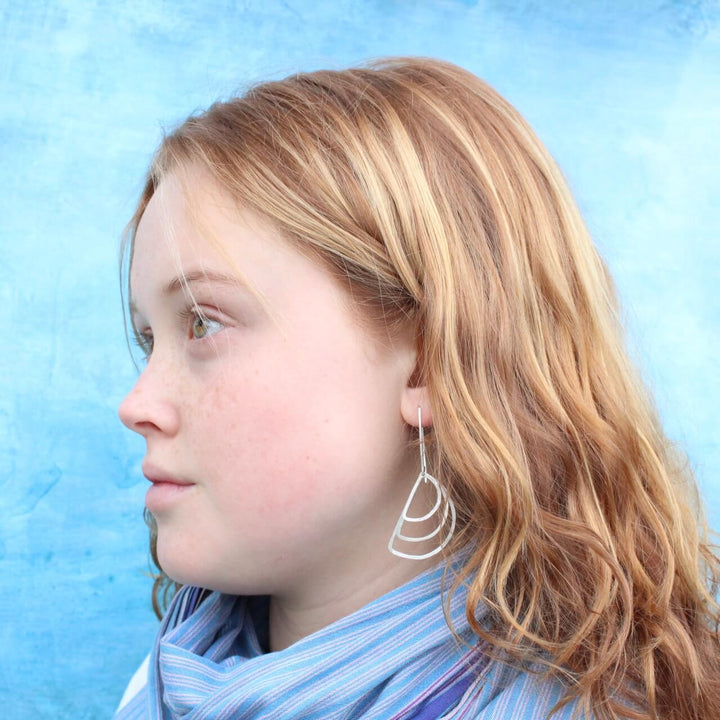 modern dangle earrings on model with scarf
